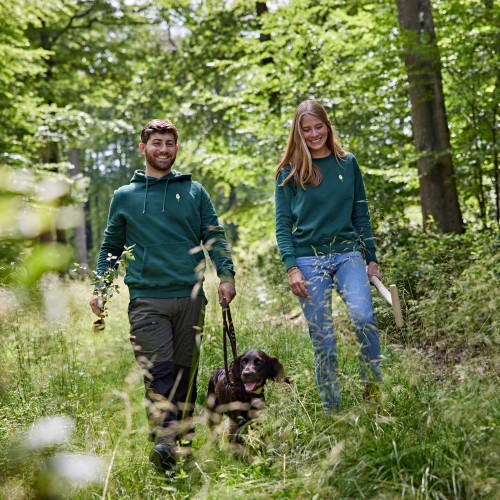 Paar mit Hund auf einem Spaziergang durch den Wald auf dem Hofgut Mappen.